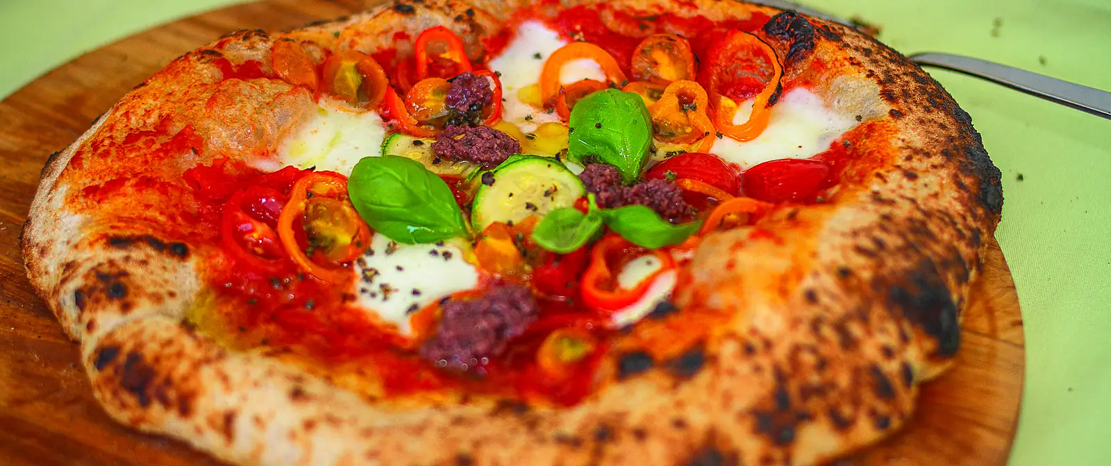 Una pizza napolitana entera, recién horneada, vista desde arriba sobre una tabla.